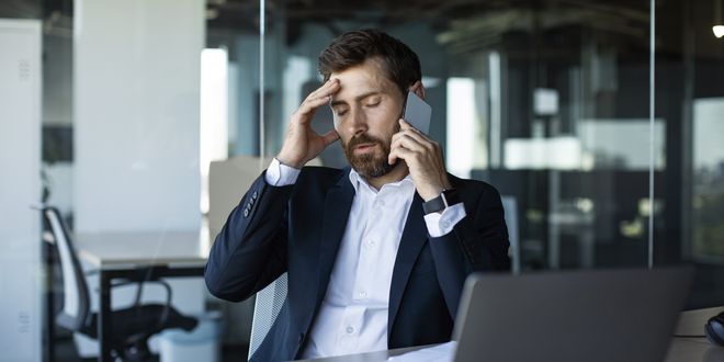 concerned-male-entrepreneur-talking-cellphone-touching-head-stress-having-unpleasant-mobile-call